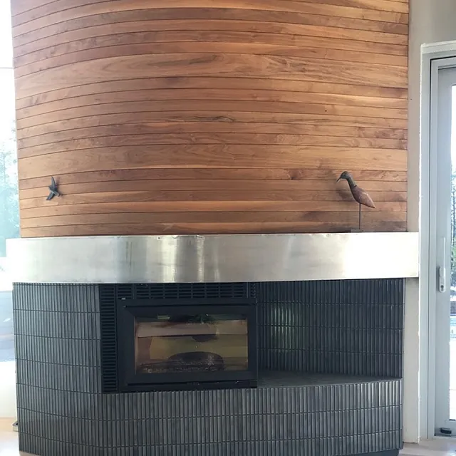 Moderne peis med mørk sokkel og trepanel, montert innendørs.