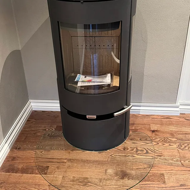 Vedovn plassert på tregulv, omgitt av lyse vegger i et hjørne.